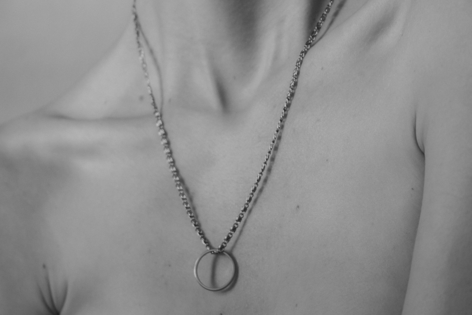 Close-up of a necklace on bare skin in grayscale, highlighting beauty and elegance.