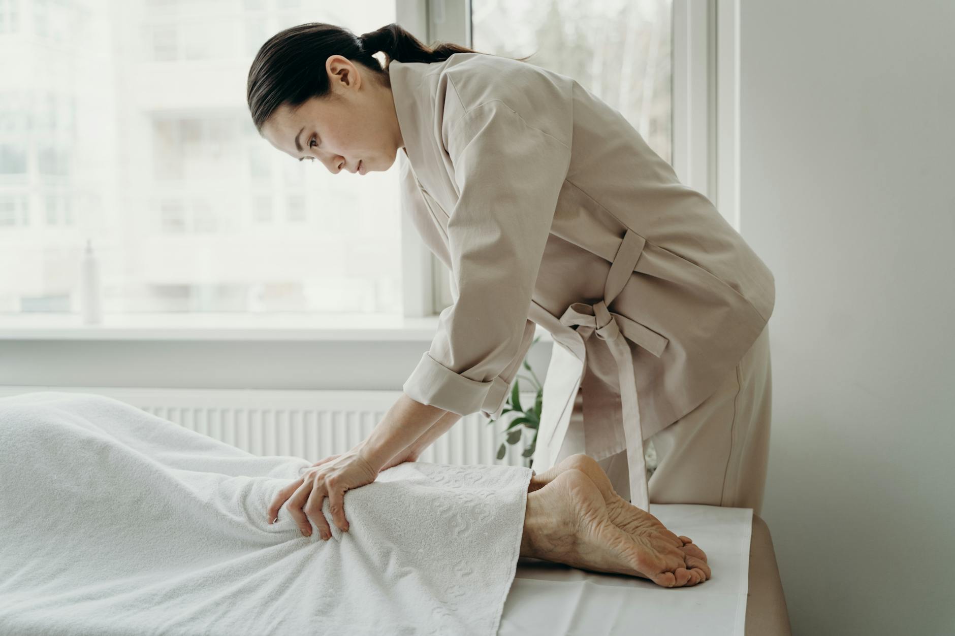 Asian female therapist providing a relaxing massage at a serene spa setting indoors.